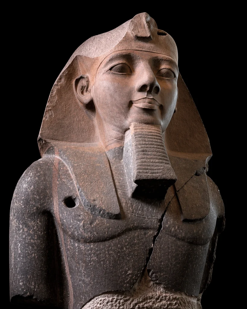 Close-up image of an ancient Egyptian stone statue from the British Museum galleries, shown against a black background.