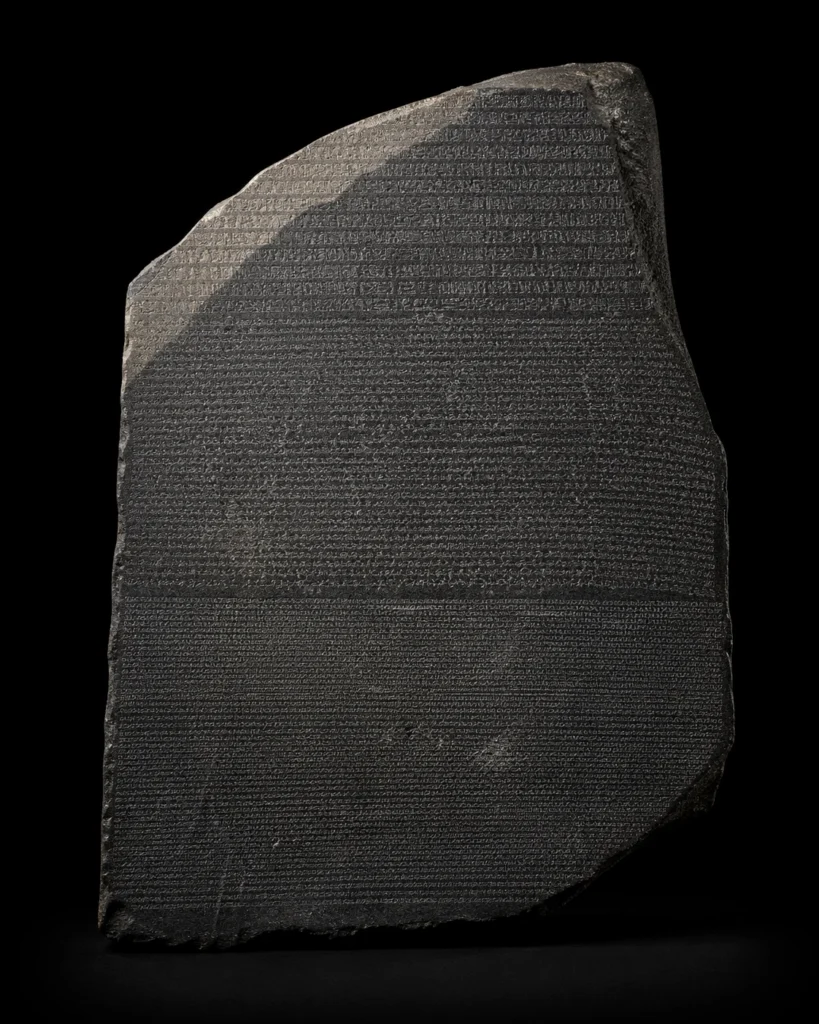 Close-up image of the Rosetta Stone against a black background, showing the inscribed surface of the famous ancient stone.