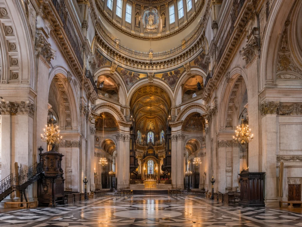 Interior view of St Paul’s Cathedral in London, showing the grand nave, soaring arches, decorative dome and high altar.